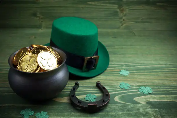 Photo of Happy St Patricks Day leprechaun hat with gold coins and lucky charms on vintage style green wood