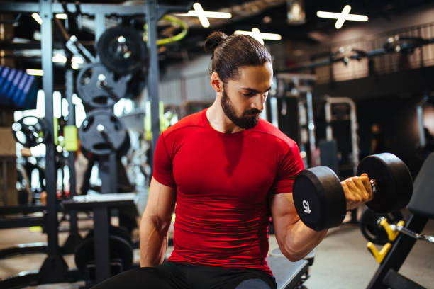 istock Young man lifting up dumbbells at the gym 1134173788