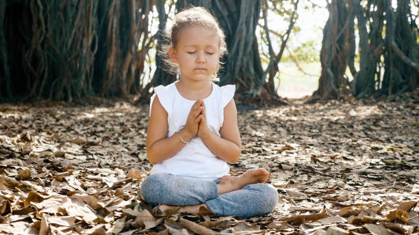 istock Little child girl meditating alone under banyan tree 1134173855