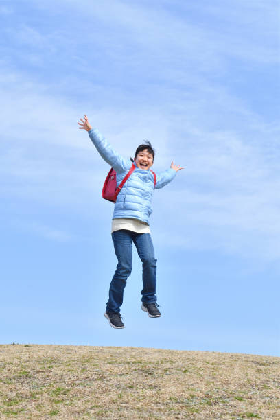 istock Japanese elementary school girl jumping  in the blue sky 1134182829