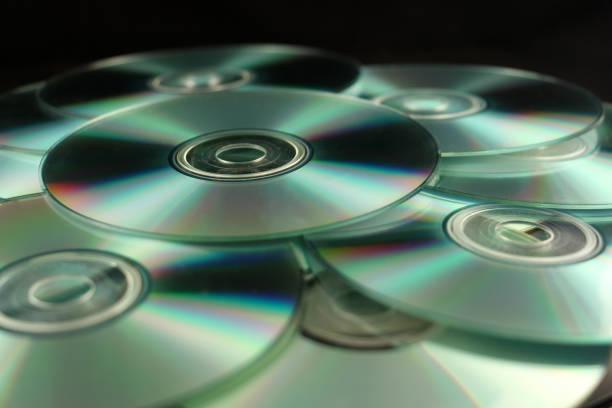Many compact disks CD on pile against black background.