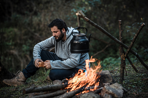 Man sitting near the campfire in camping.  Outdoor activity in summer.