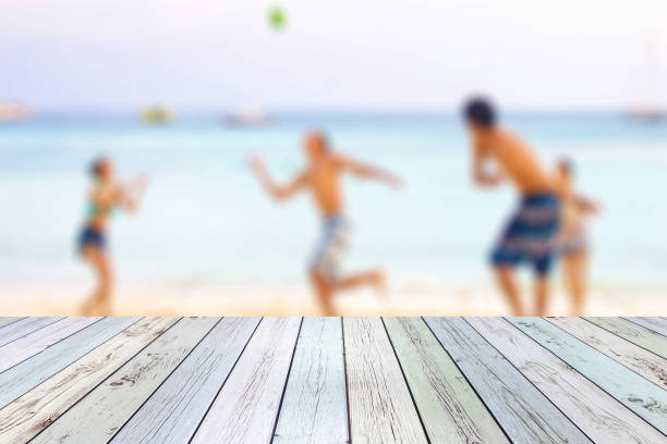 istock White wood table on blurred young tourists playing ball on beach 1134187413