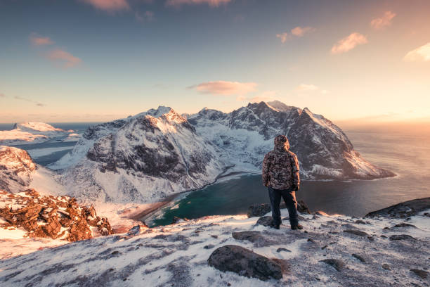 istock Man mountaineer standing on snowy mountain at sunset 1134187443