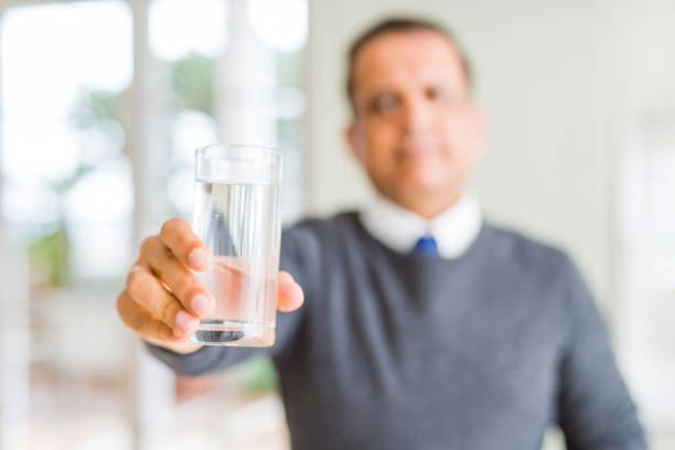 istock Middle age man drinking glass of water at home with a confident expression on smart face thinking serious 1134189542