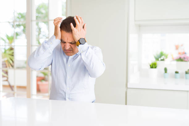istock Middle age man sitting at home suffering from headache desperate and stressed because pain and migraine. Hands on head. 1134189737