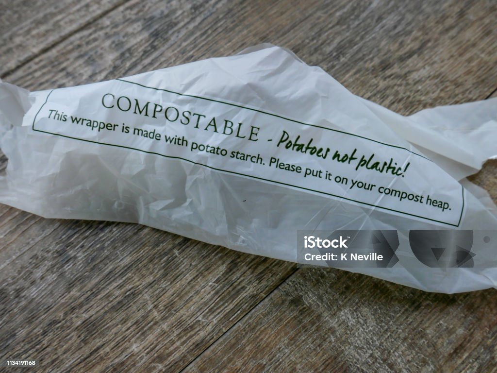 Potato starch compostable wrapper A biodegradable potato starch compostable wrapper lying on a wooden floor, made as an alternative to plastic packaging, which will help save the environment and it needing to go to landfill as a more environmentally friendly product. Packaging Stock Photo