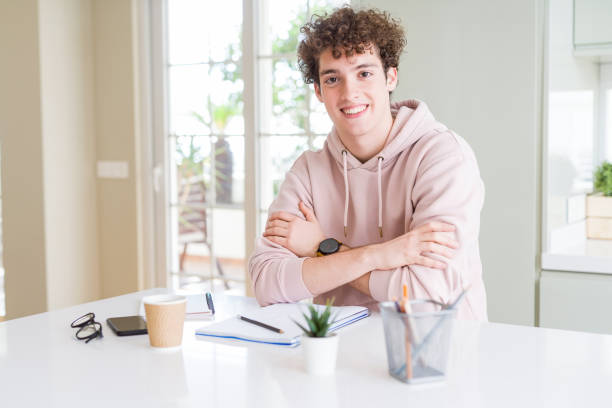 istock Young student man writing on notebook and studying happy face smiling with crossed arms looking at the camera. Positive person. 1134191296