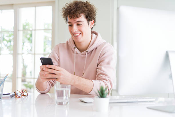 istock Young student man using smartphone and computer with a happy face standing and smiling with a confident smile showing teeth 1134191302