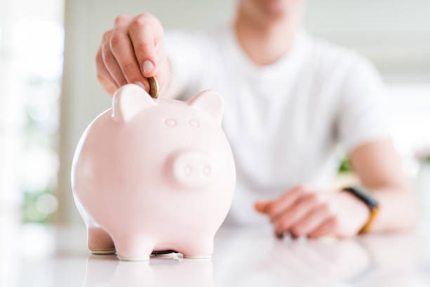 Close up of man putting a coin inside piggy bank as saving or investment Close up of man putting a coin inside piggy bank as saving or investment only teenage boys stock pictures, royalty-free photos & images