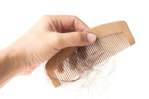 Human hand holding comb with lost hair on it, isolated on white background.