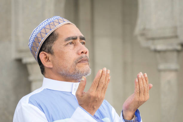 istock Close-Up Of Man Praying While Standing At Mosque 1134193961