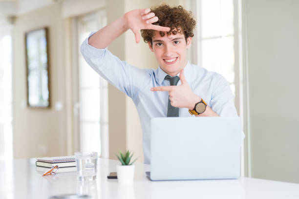istock Young business man working with computer laptop at the office smiling making frame with hands and fingers with happy face. Creativity and photography concept. 1134194126