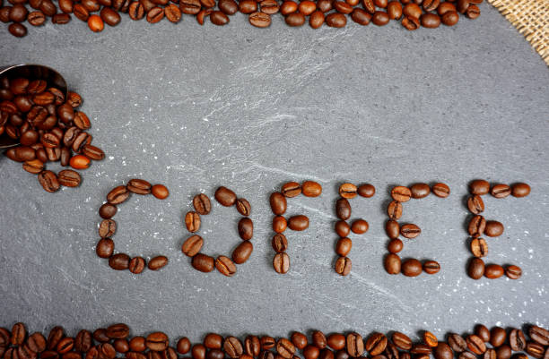 istock Coffee text with coffee beans and loose beans at grey kitchen background 1134194228