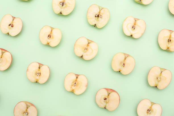istock Background of cut in half apples on green background 1134195336