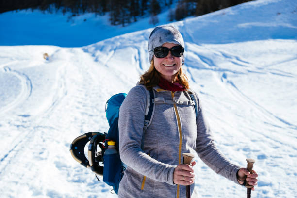 Blond woman with turqoise daypack is having fun on a snowshoe tour in south tirol stock photo