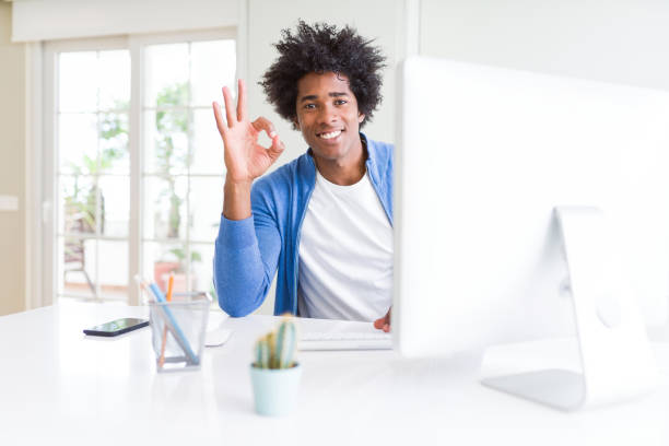 istock African American man working using computer doing ok sign with fingers, excellent symbol 1134197010