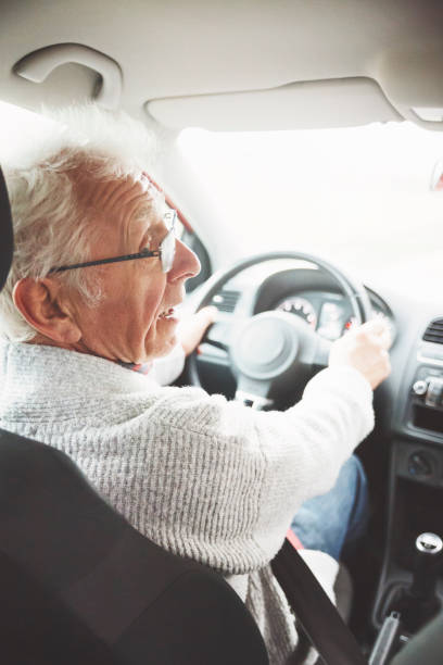 old man drives his car and looks over his shoulder - old men car vertical imagens e fotografias de stock