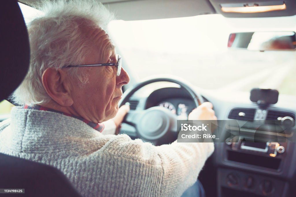 Old gentleman drives car Friendly old gentleman with metal frame glasses drives car Driving Stock Photo