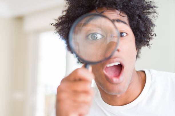 istock African American man looking through magnifying glass scared in shock with a surprise face, afraid and excited with fear expression 1134199607