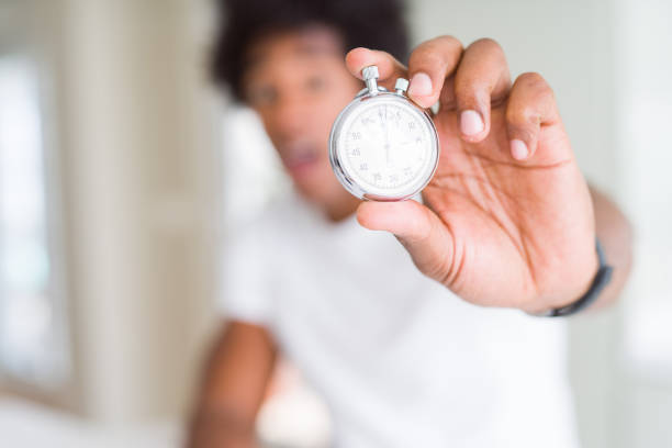 istock African American man holding stopwatch scared in shock with a surprise face, afraid and excited with fear expression 1134199742