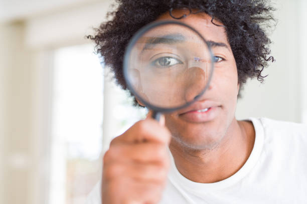 istock African American man looking through magnifying glass with a confident expression on smart face thinking serious 1134201131