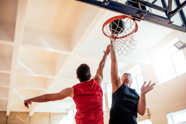 Reaching for that slam dunk! Photo of two basketball players dunking basketball in hoop. taking a shot sport stock pictures, royalty-free photos & images