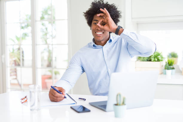 istock African American business man working writing on notebook with happy face smiling doing ok sign with hand on eye looking through fingers 1134202171
