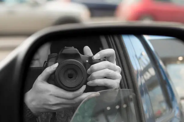 Photo of Reflection in side view mirror of someone with DSLR camera