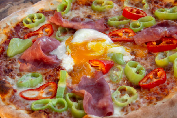 istock Pizza with  ham, egg, fresh green and red peppers. Closeup. 1134208110