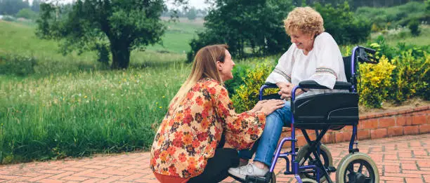 Photo of Young woman talking to elderly woman in a wheelchair