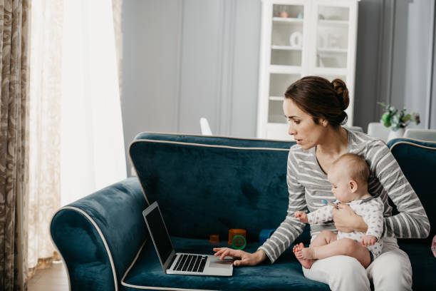 istock Charming mother holding her baby in arms while working on laptop 1134212821