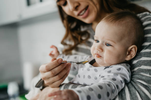 istock Young mother feeding from spoon her baby indoors 1134212935