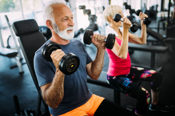 старший подходят мужчина и женщина делают упражнения в тренажерном зале, чтобы оставаться здоровым - exercising sport gym spinning стоковые фото и изображения