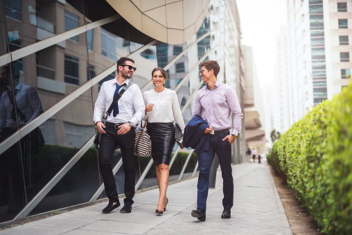 Full length of smiling businesspeople discussing about a meeting while walking in the city.