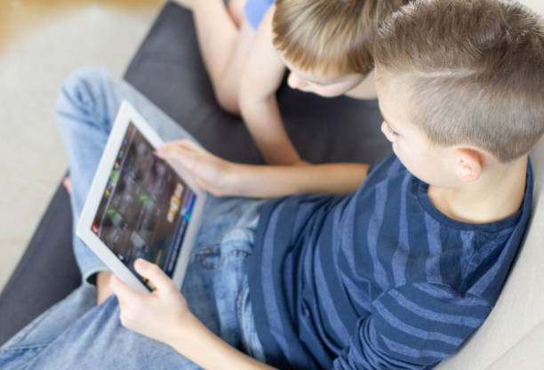 istock Two kids using tablet at home. Brothers with tablet computer in light room. Boys playing games on tablet pc, emotions. Children and devices concept 1134221947