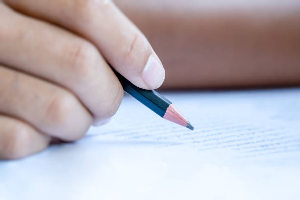 Pencil on hand writing answer on paper in examination