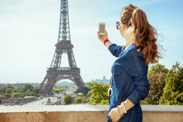 istock woman against Eiffel tower taking photo with smartphone 1134223112