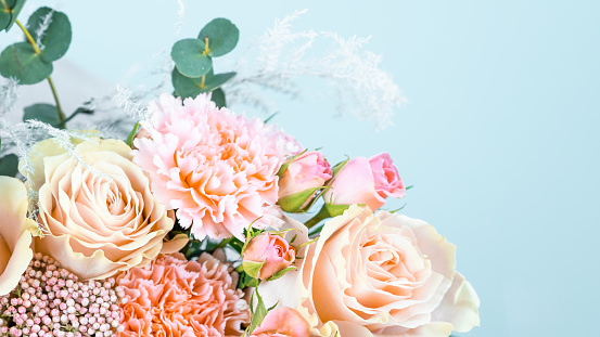 Beautiful bouquet with pink carnations and roses close-up on a blue background, place for text.