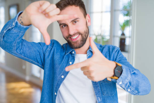 istock Handsome man at home smiling making frame with hands and fingers with happy face. Creativity and photography concept. 1134228633