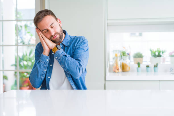 istock Handsome man at home sleeping tired dreaming and posing with hands together while smiling with closed eyes. 1134229546