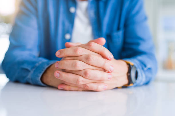 Close up of man crossed hands over white table