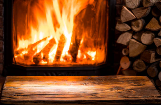 istock Old wooden table and fireplace with warm fire. 1134231686