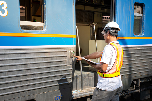 Picture of Asian engineer wearing safety helmet with checking train for maintenance in station/Engineer Concept