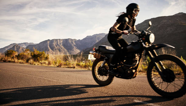 Eating up those miles Shot of a young woman riding her motorcycle through the countryside motorcycle biker stock pictures, royalty-free photos & images