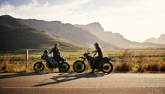 Shot of two young women riding their motorcycles through the countryside