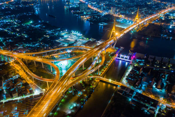 vista aérea da cruz da ponte de suspensão de bhumibol sobre o rio de chao phraya na cidade de banguecoque com o carro na ponte na noite em banguecoque tailândia. - bridge bangkok suspension bridge river - fotografias e filmes do acervo
