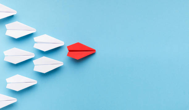 One blue paper plane leading group of white ones New trends concept. One red paper plane followed by group of white ones on blue background, copy space paper airplane photos stock pictures, royalty-free photos & images