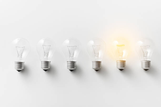 illuminated light bulb in row of dim ones - light bulb business wisdom abstract imagens e fotografias de stock