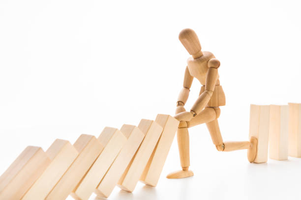 istock Wooden mannequin stopping domino effect on white 1134238813